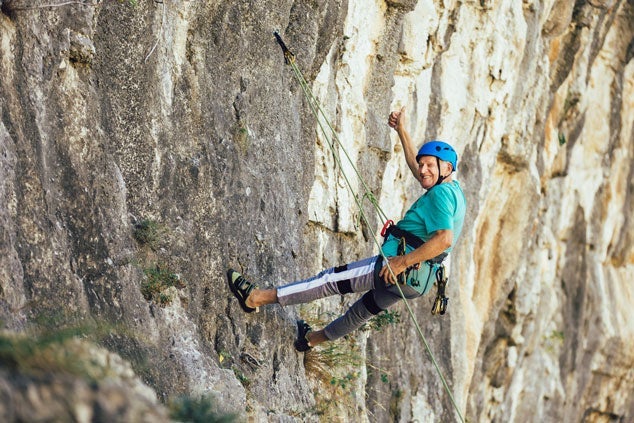 A man rockclimbing secured by a rope harness