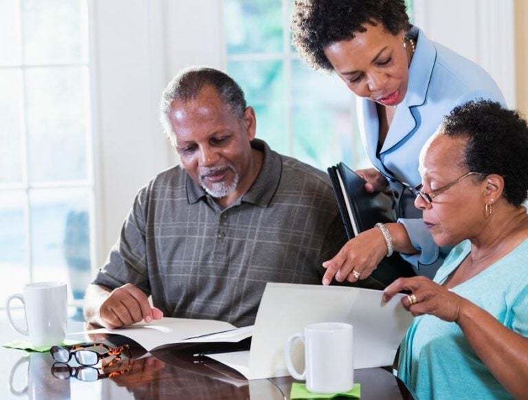 A couple discussing the tradeoffs of a reverse mortgage with a financial advisor|A couple discussing the tradeoffs of a reverse mortgage with a financial advisor