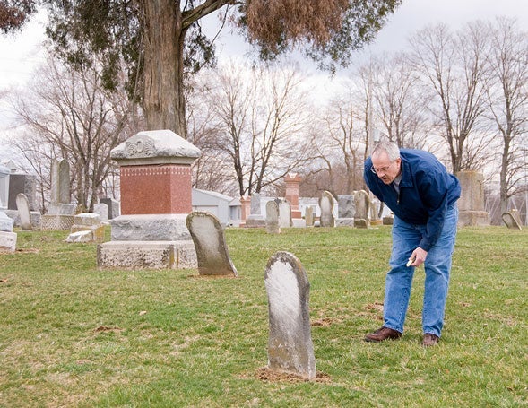 A man tracing his family tree in an old cemetary|